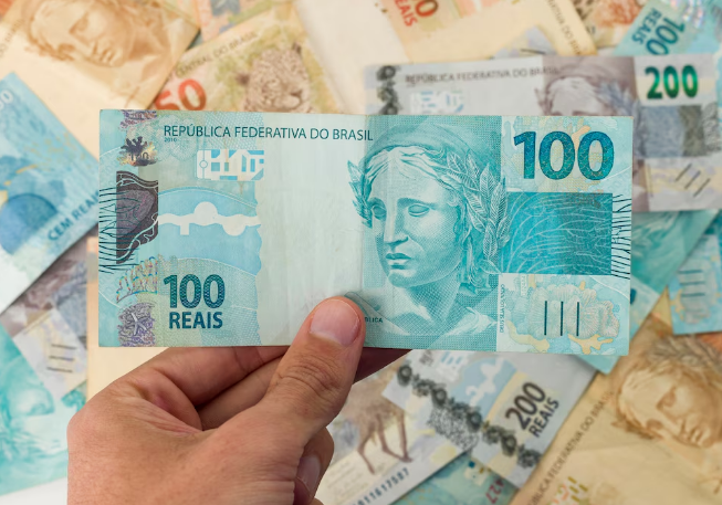 Detalhe de uma cédula de 100 reais com foco na figura simbólica da República