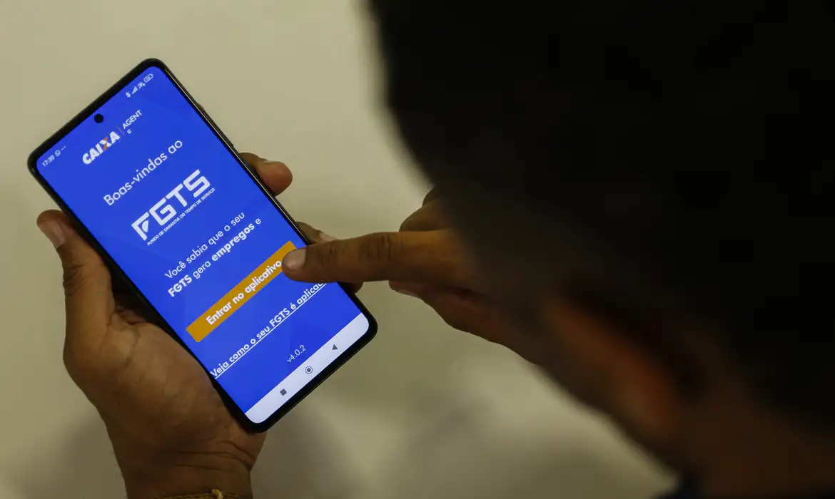 "Pessoa utilizando o aplicativo da Caixa Econômica Federal para consultar o FGTS no celular."
