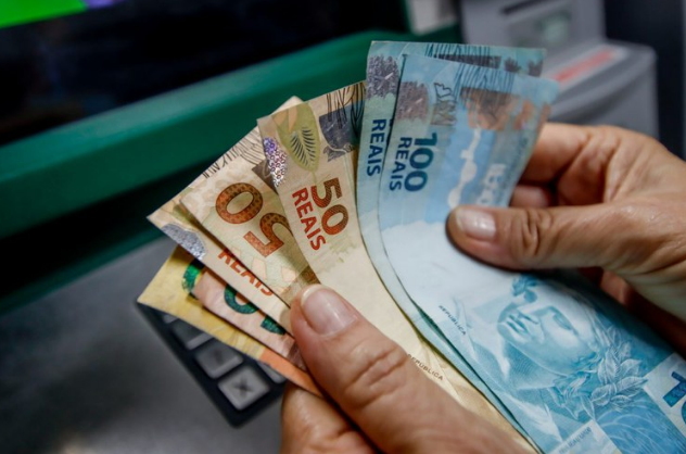 Aposentados segurando notas de reais do INSS, representando a devolução de valores.