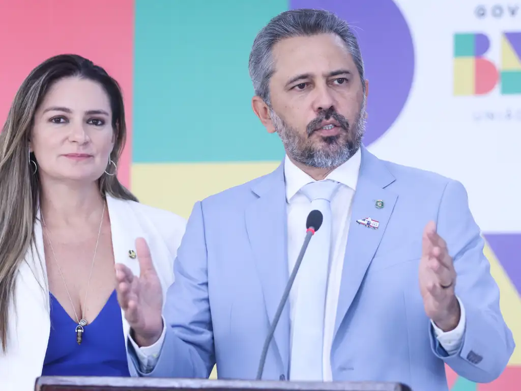 Governador Elmano de Freitas falando em evento oficial ao lado de mulher, destacando medidas para servidores estaduais