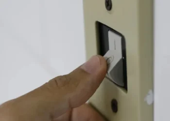 Interruptor de luz sendo acionado, simbolizando o aumento da conta de energia devido à bandeira vermelha.