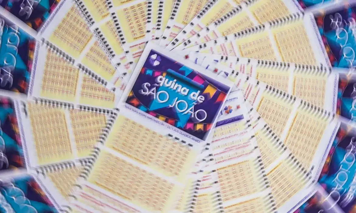 Bilhetes da Quina de São João espalhados ao redor de um folheto com design colorido e festivo.