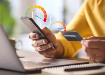 Pessoa consultando score de crédito pelo celular com cartão na mão