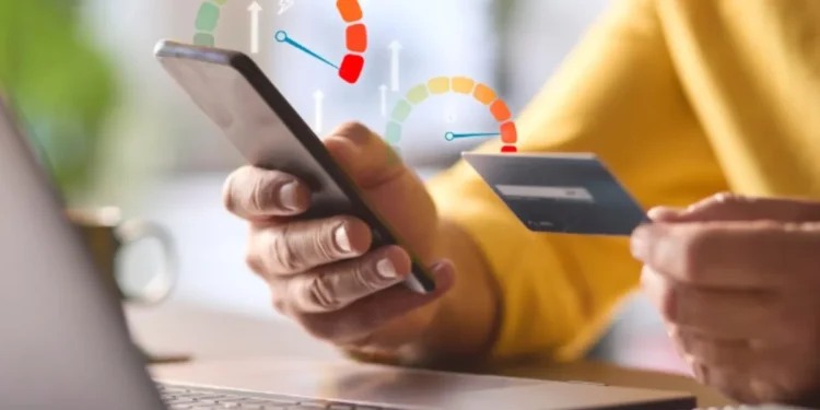 Pessoa consultando score de crédito pelo celular com cartão na mão