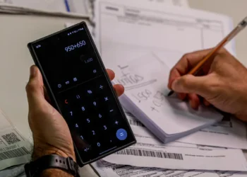 Pessoa usando calculadora no celular para organizar pagamentos e parcelas.