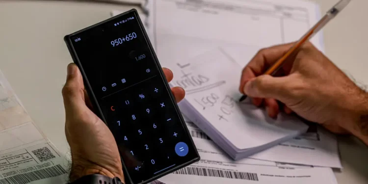Pessoa usando calculadora no celular para organizar pagamentos e parcelas.