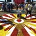 Pessoas confeccionando um tapete colorido de flores para celebração religiosa durante o feriado de Corpus Christi.