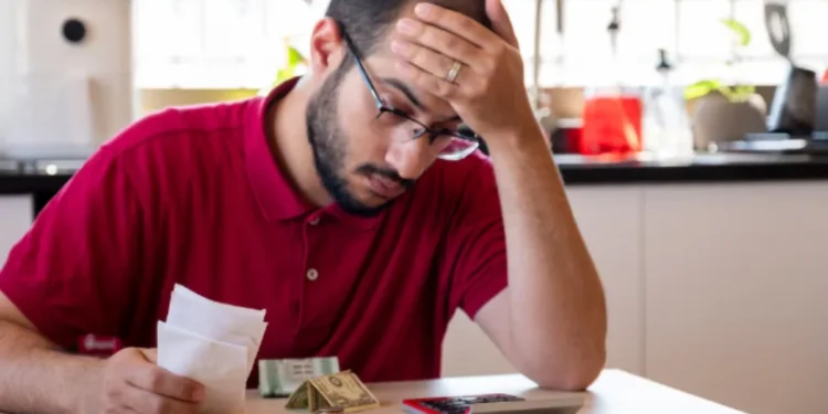 Homem preocupado analisando contas, dinheiro e calculadora
