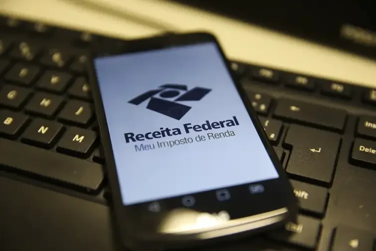 Aplicativo da Receita Federal aberto na tela de um smartphone sobre um teclado