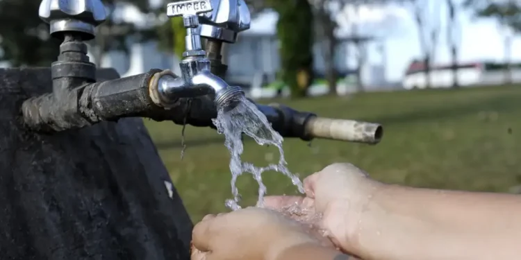 Pessoas aproveitando a tarifa social de água, com desconto de até 78%, ao se hidratar diretamente de um ponto de água.