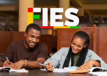 Estudantes sorrindo enquanto estudam juntos no FIES 2025, com livros e canetas na mesa.