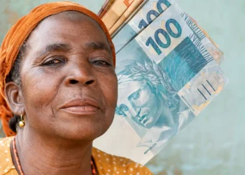 Idosa sorrindo com notas de dinheiro, representando o pagamento de R$ 1.518 para idosos e pessoas com deficiência a partir da próxima semana.