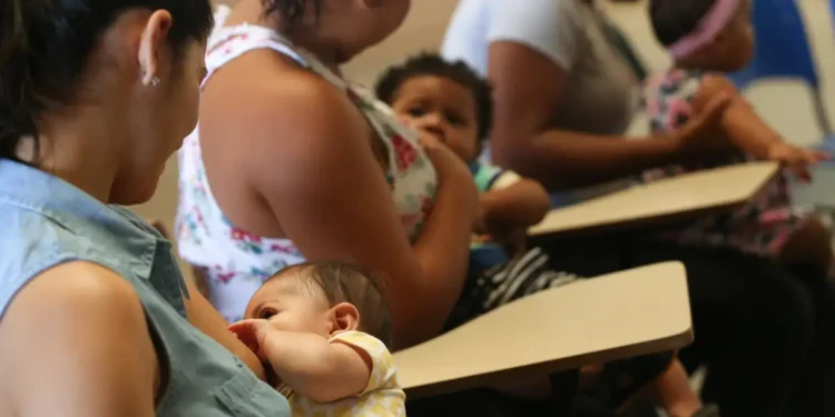 Mulheres com bebês no colo aguardam atendimento para programas sociais.