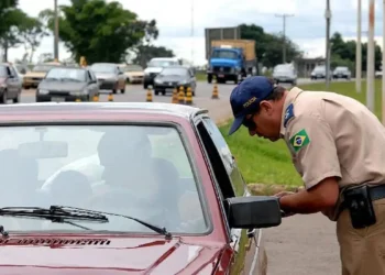 Policial abordando veículo durante fiscalização em rodovia