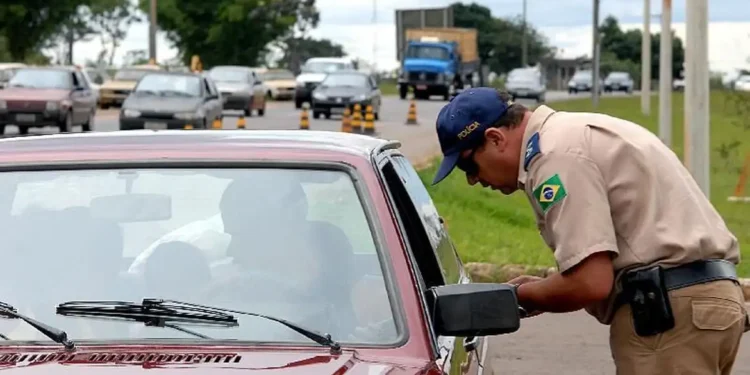 Policial abordando veículo durante fiscalização em rodovia