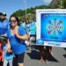 Imagem de evento de conscientização sobre autismo, com pessoas participando de uma caminhada com cartazes e roupas azuis, celebrando o Dia Mundial de Conscientização do Autismo.