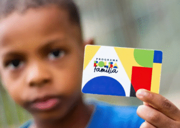 Criança segurando cartão do Programa Bolsa Família, com fundo desfocado.