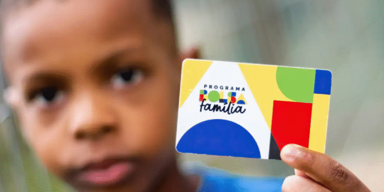 Criança segurando cartão do Programa Bolsa Família, com fundo desfocado.
