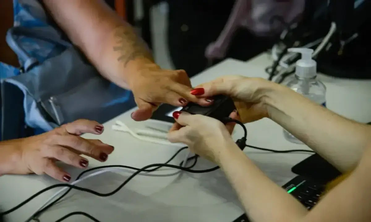 Pessoa realizando biometria digital para acessar benefícios sociais.
