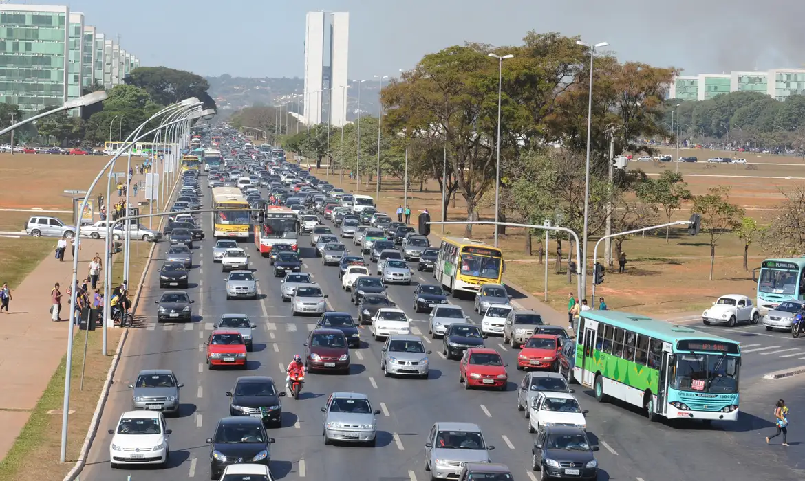 Trânsito intenso com diversos veículos e ônibus em avenida movimentada
