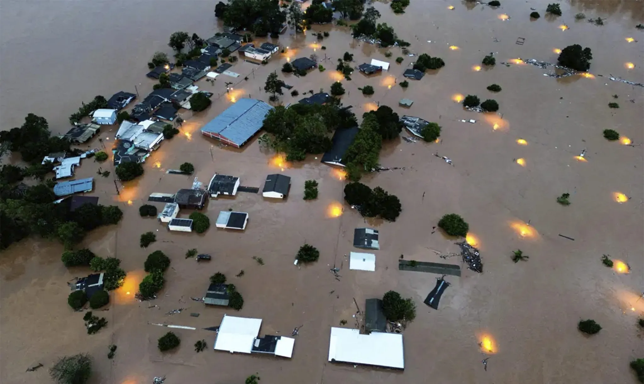 Imagem aérea de cidade inundada mostrando casas parcialmente submersas devido a calamidade.