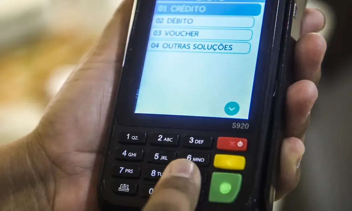 Pessoa selecionando forma de pagamento em maquininha de cartão