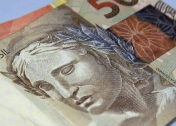 Nota de cinco reais, representando dinheiro brasileiro usado em transações financeiras, como na antecipação de salário.