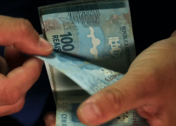 Dinheiro em espécie sendo retirado da carteira, relacionado a valores a receber do CPF.