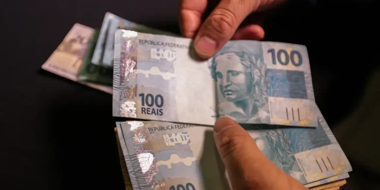 Pessoa segurando notas de 100 reais representando prêmio de loteria acumulado