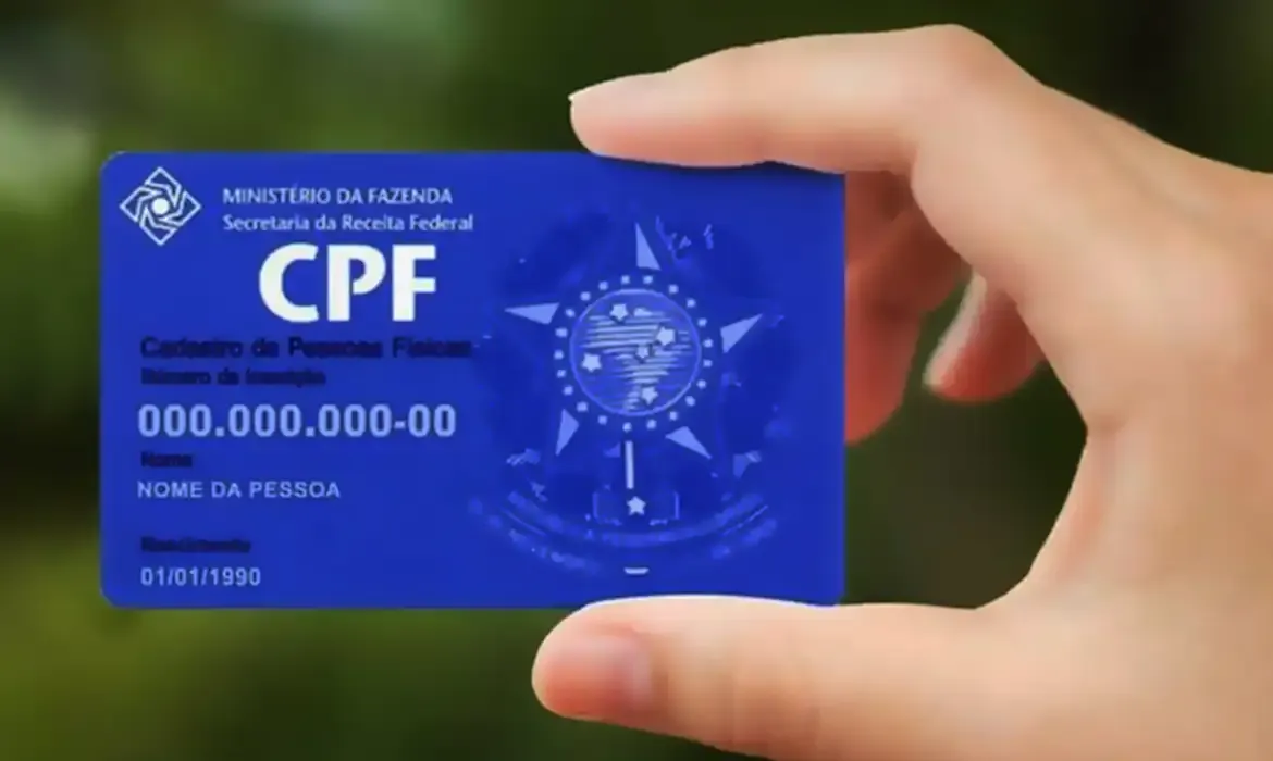 Pessoa segurando cartão do CPF com dados fictícios