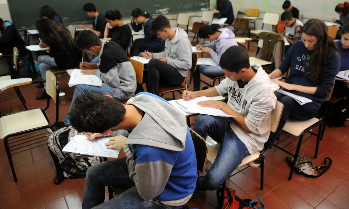 Estudantes em sala de aula realizando prova escolar