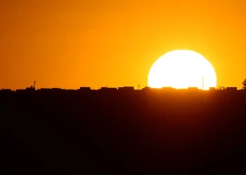 Pôr do sol com silhueta de cidade, destacando o horizonte dourado e luminoso.