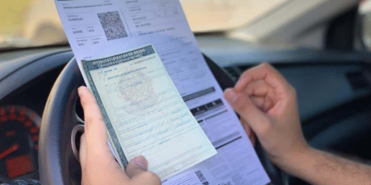 Criminosos clonam site do IPVA para aplicar golpes, documento sendo segurado dentro de um carro.