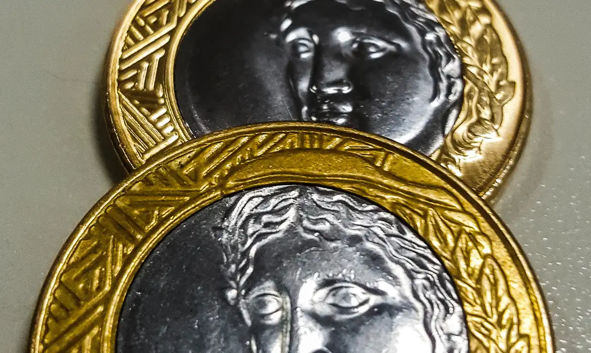 Detalhe ampliado da face de moedas de R$1 com borda dourada