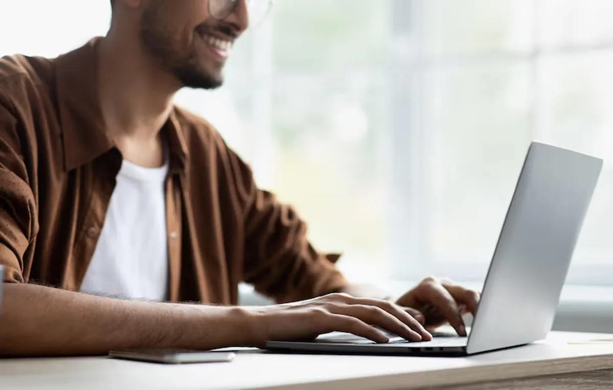 Pessoa jovem trabalhando no computador, destacando informações sobre o cronograma e os valores das bolsas do Pé-de-Meia Licenciaturas.