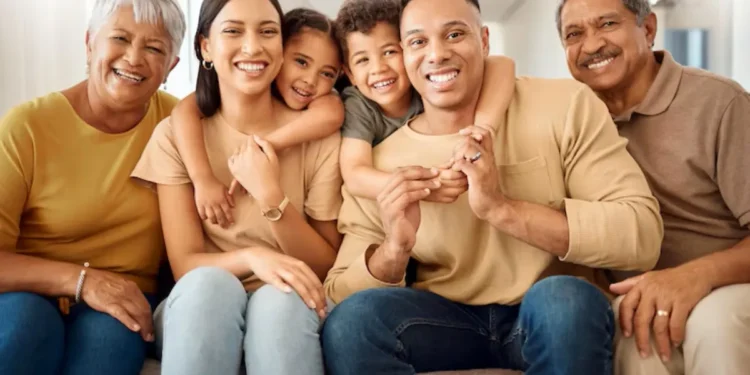 Família sorrindo e posando para uma foto, incluindo avós, pais e crianças, representando união e felicidade.