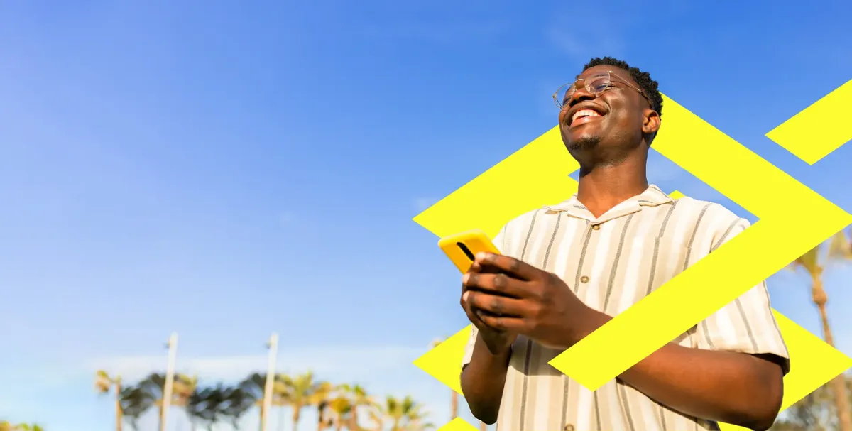 Homem sorrindo e usando smartphone, representando a consulta para sacar dinheiro esquecido.