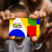 Mãos de uma criança segurando o cartão do programa Bolsa Família, com o novo design colorido e a logo do governo. A imagem representa o apoio financeiro e a inclusão social oferecidos a milhões de famílias no Brasil.