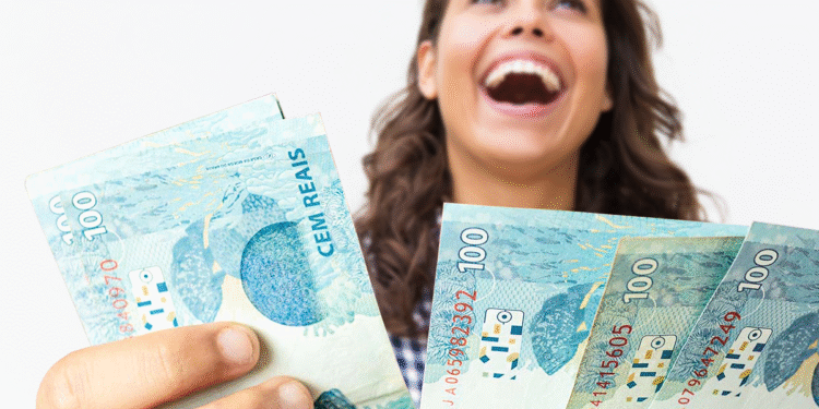 Pessoa feliz segurando cédulas de R$100, representando a possibilidade de resgatar dinheiro esquecido.