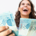 Pessoa feliz segurando dinheiro após aumento do salário mínimo.