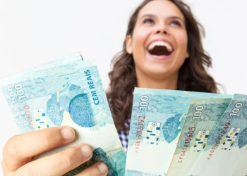 Pessoa sorrindo e segurando cédulas de R$ 100 reais, possivelmente associada a prêmio em sorteio.