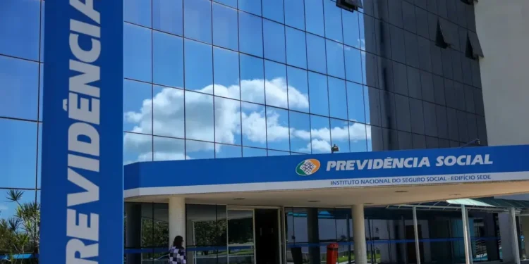 Imagem do prédio da Previdência Social, do Instituto Nacional do Seguro Social (INSS), com céu limpo ao fundo, em frente a uma pessoa caminhando.