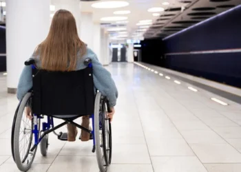 Pessoa em cadeira de rodas em estação moderna e acessível de metrô, representando inclusão e mobilidade.