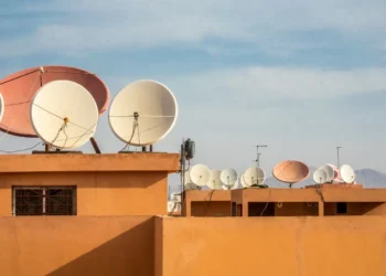 Antenas parabólicas em telhados de uma cidade, com diversas unidades de satélite.