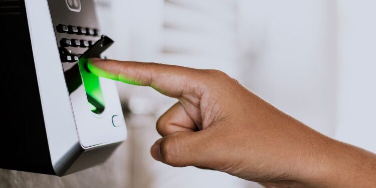 Pessoa usando leitor biométrico com luz verde acesa.