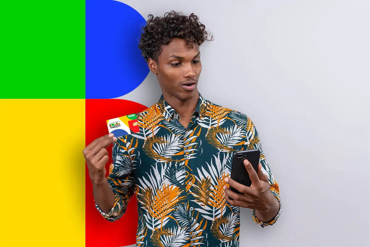 Homem consultando o calendário do Bolsa Família no celular enquanto segura um cartão do programa.