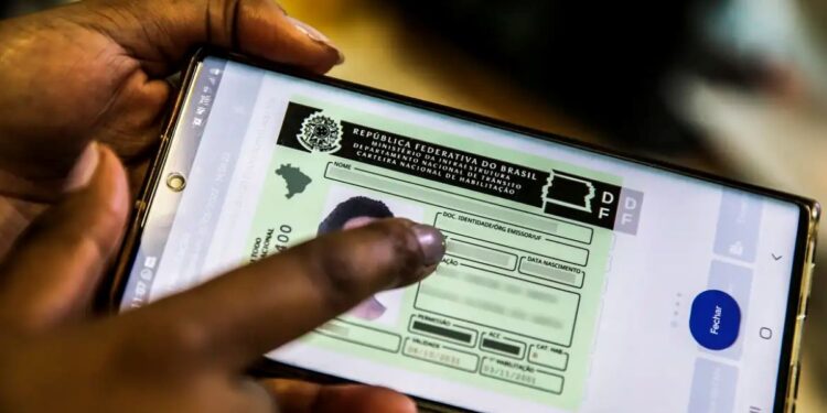 A imagem de uma mão segurando um smartphone com a Carteira Nacional de Habilitação (CNH) digital exibida na tela.