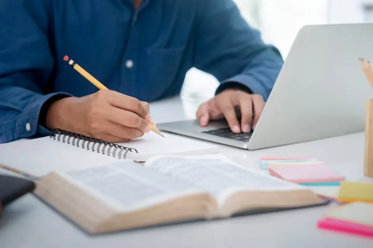 Jovem estuda online com caderno, computador e material didático