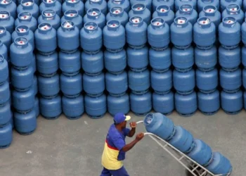 Homem carregando botijão de gás em estoque para o programa 'Gás para Todos'.