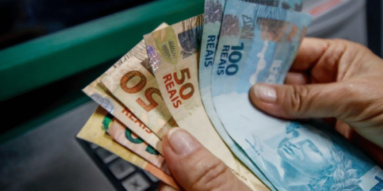Pessoa retirando dinheiro em caixa eletrônico, com notas de 50 e 100 reais, tema relacionado ao saque especial.